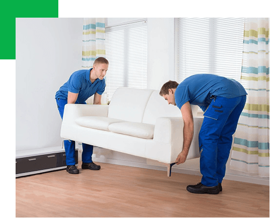 Two men wearing blue lifting a sofa in a home